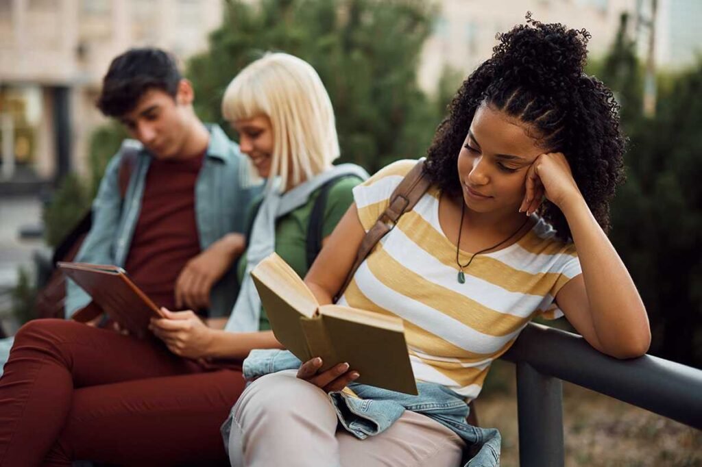 Jovem mulher negra lendo um livro no campus da faculdade