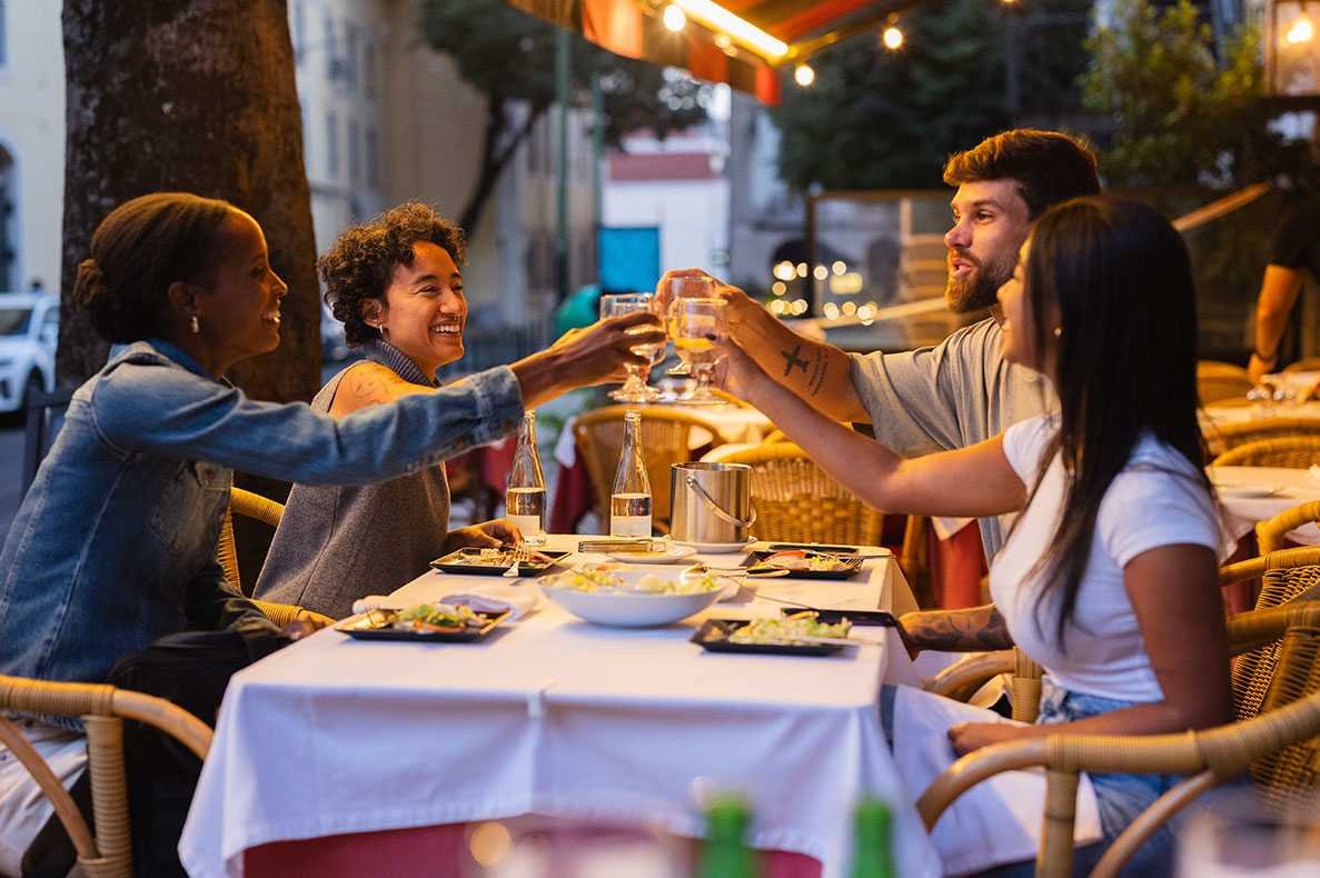 Amigos brindando bebidas num restaurante em Lisboa, Portugal