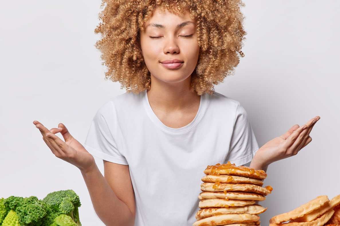 Mulher zen medita com os olhos fechados á frente de uma mesa com comida