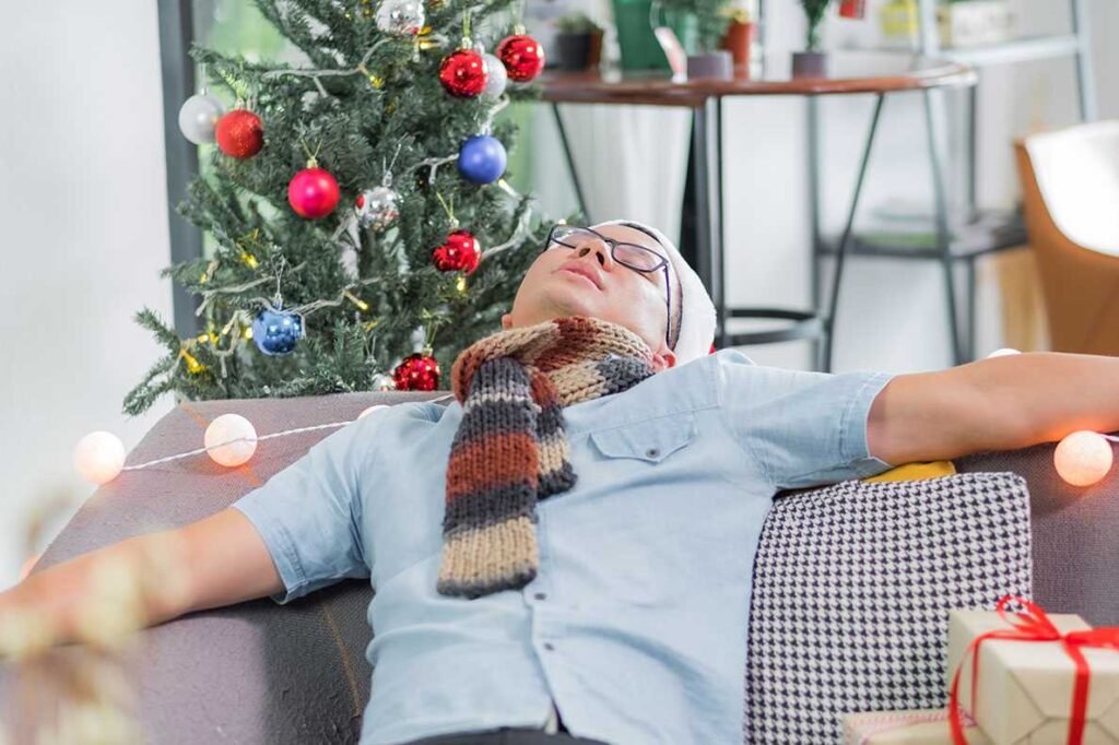 Homem asiático de ressaca dorme no sofá depois de um Natal pesado