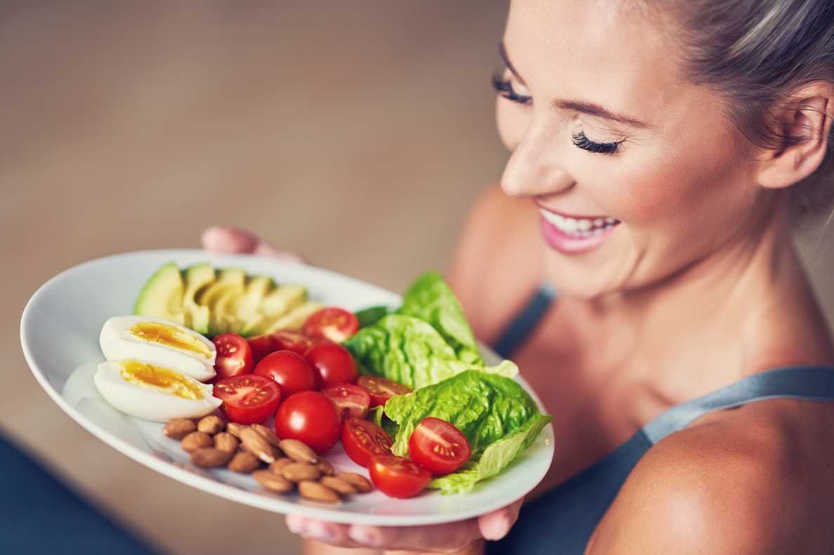 Mulher adulta comendo almoço saudável e sentada no tapete de ioga