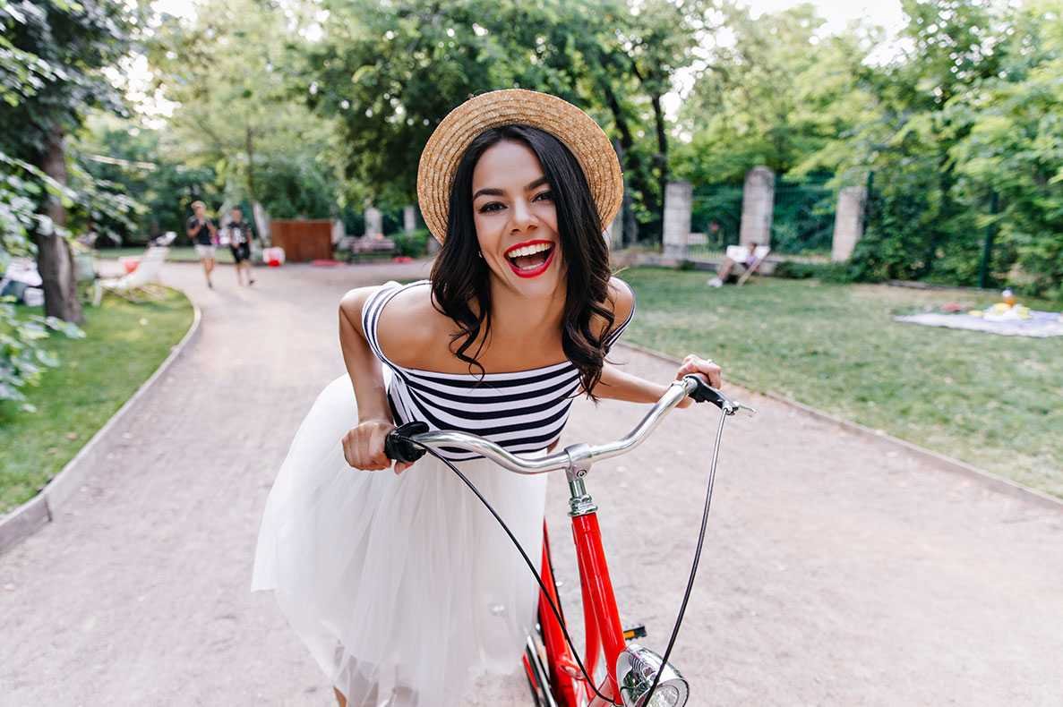 Mulher feliz a passear num parque com uma bicicleta vermelha