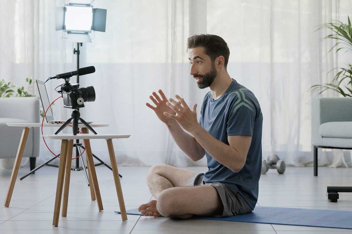 Um sentado num tapete de yoga em casa em frente de uma camara
