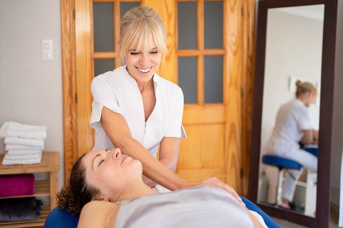 Mulher faz massagem fisioterapeutica a outra mulher deitada numa marquesa