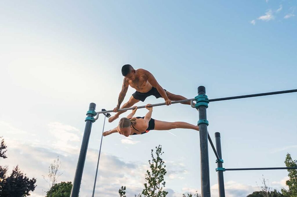 Casal a fazer calistenia num parque publico