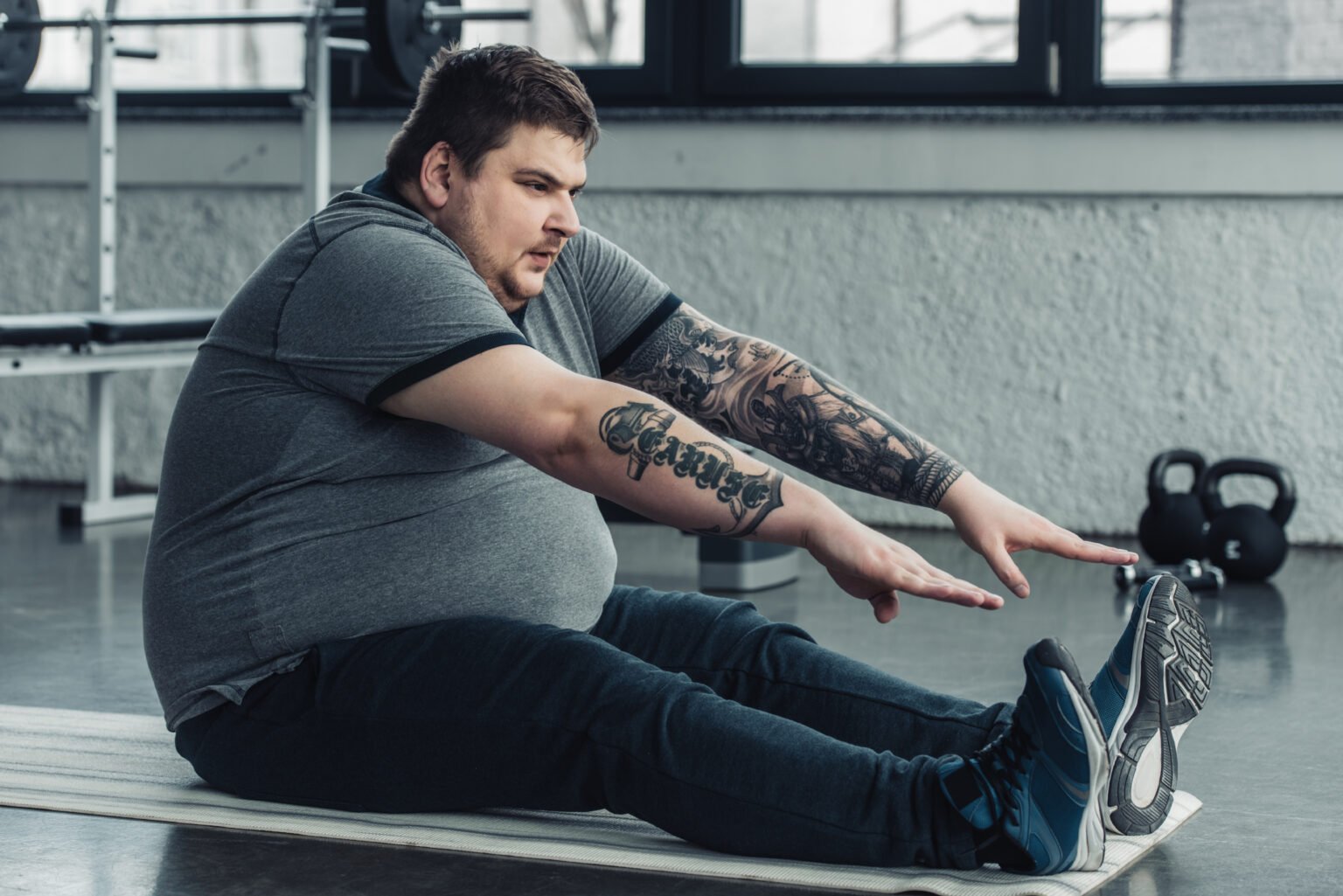 Homem com peso a mais a fazer abdominais no ginásio