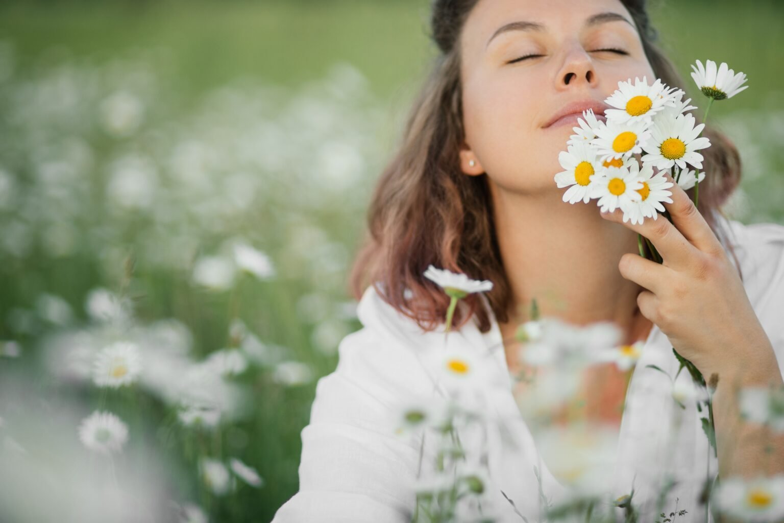 Jovem mulher a cheirar flores no cmapo